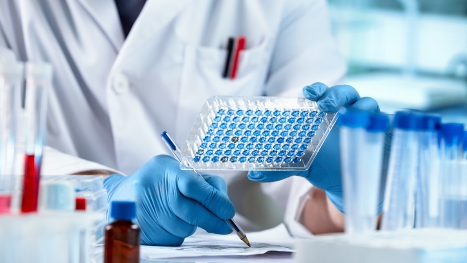 A man in a lab coat is holding a test tube.