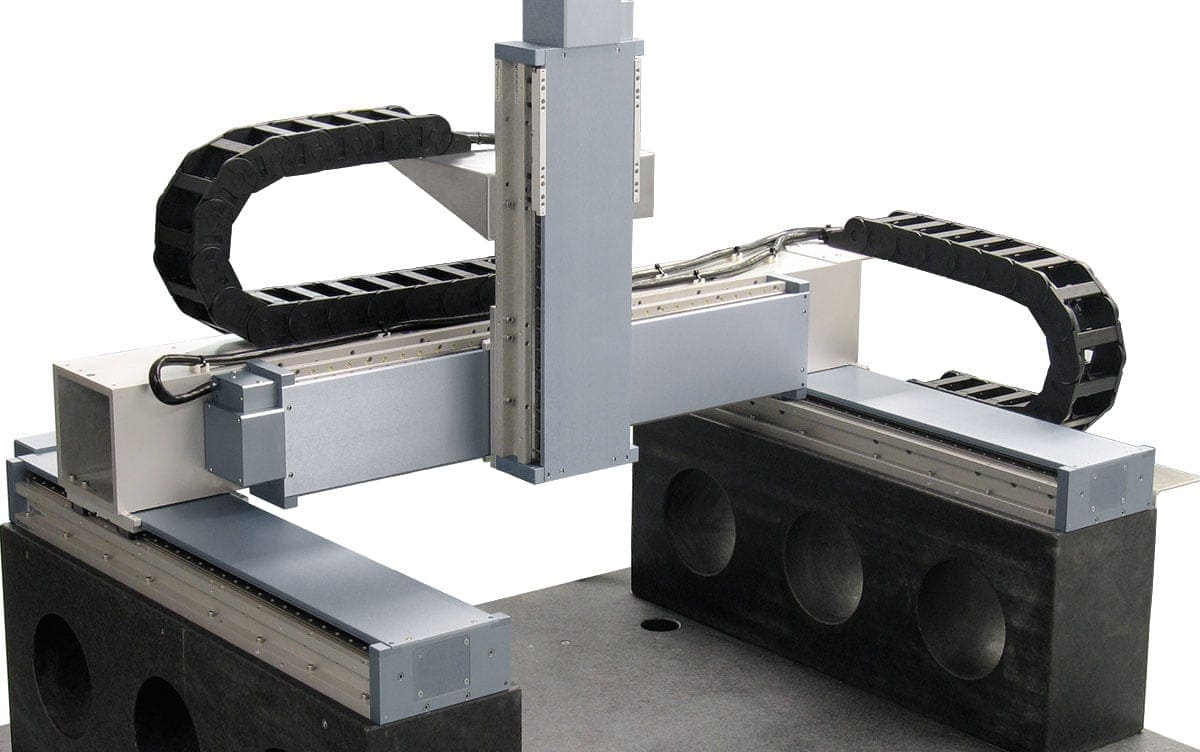 Image of an industrial robotic arm surrounded by metal framework, wiring, and cable management systems, likely used for manufacturing or assembly processes.