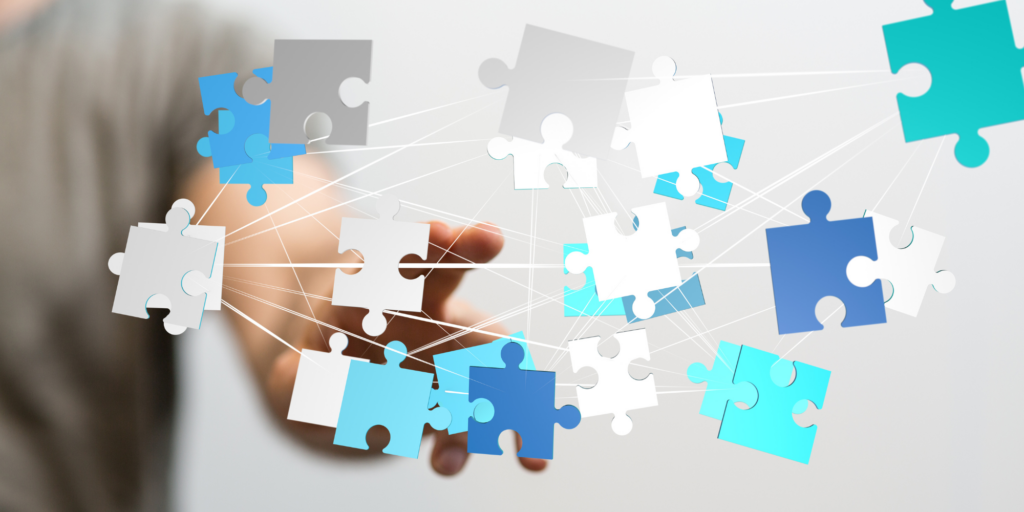 A person interacts with an augmented reality display of interconnected blue and white puzzle pieces.