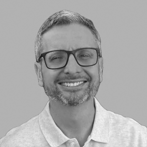 Smiling person wearing glasses and a polo shirt, posing against a plain background.